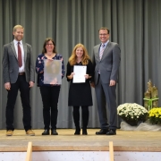 Vier Personen auf Bühne mit Urkunden posierend