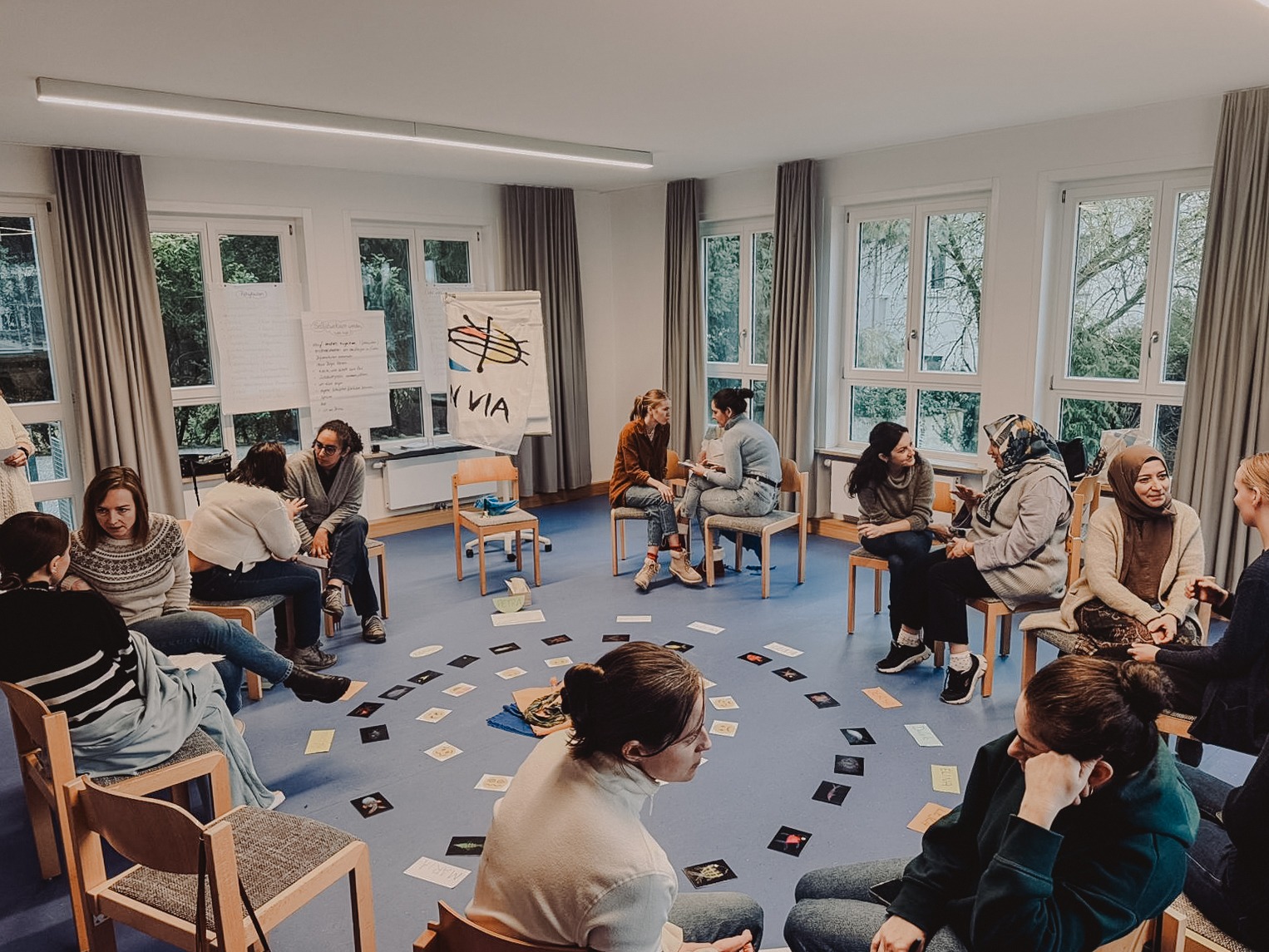 Gruppe von Menschen in einem Stuhlkreis mit geschmückter Mitte