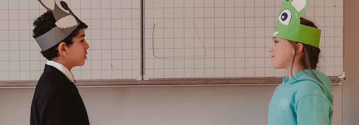 Zwei verkleidete Kinder stehen sich in einem Klassenzimmer gegenüber.
