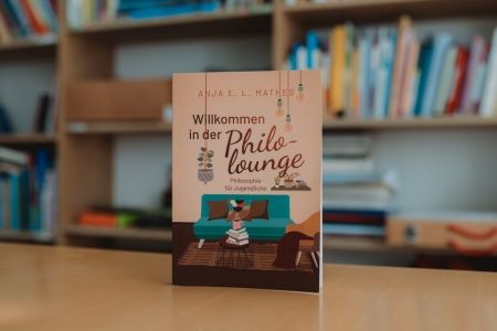 Das Buch "Willkommen in der Philolounge" steht auf einem Tisch.